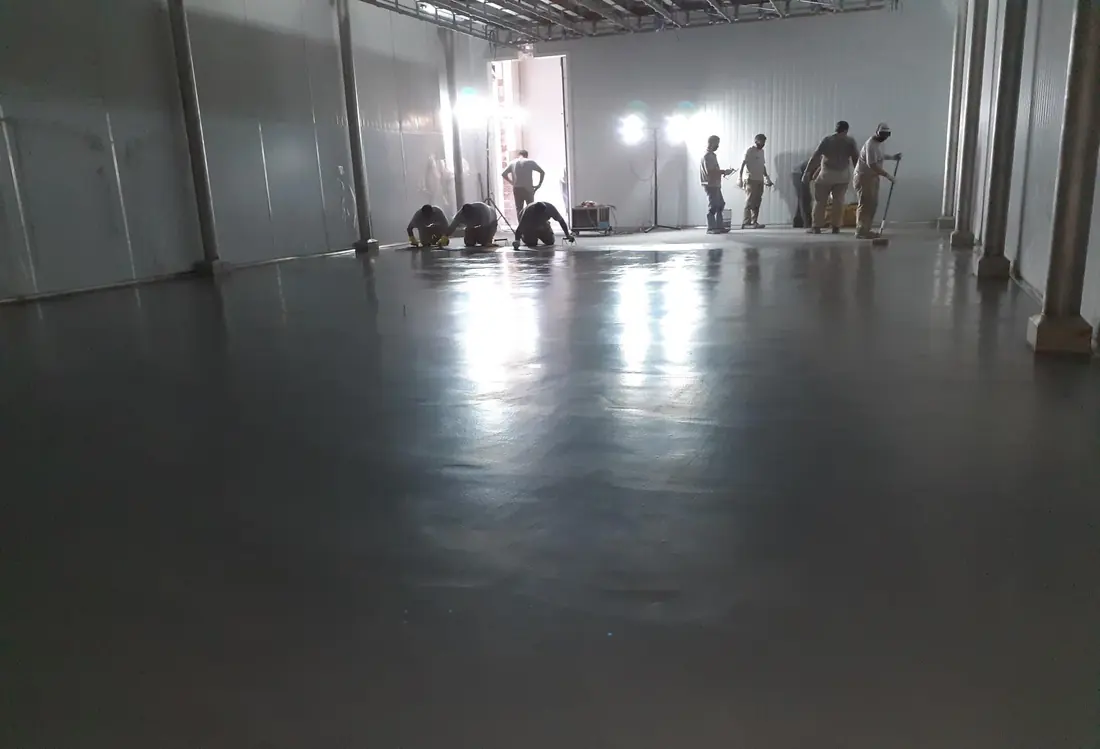 Cámara de congelado de un frigorífico con piso de mortero de poliuretano-cemento de 9 mm terminado, con la cuadrilla trabajando al fondo
